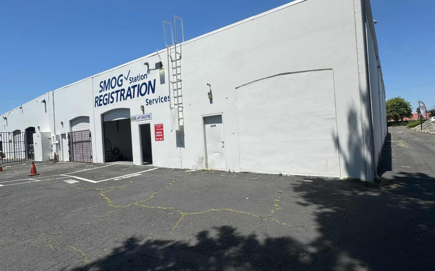 SMOG Station and Registration Services lettering on the front of the building on Greenback Lane, with the bay door open