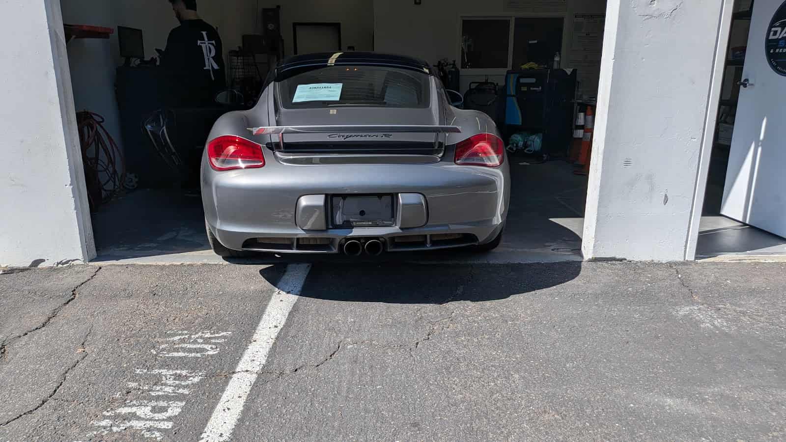Silver Porsche pulled nose-first into the shop's open inspection bay, with a paper notice on its rear window