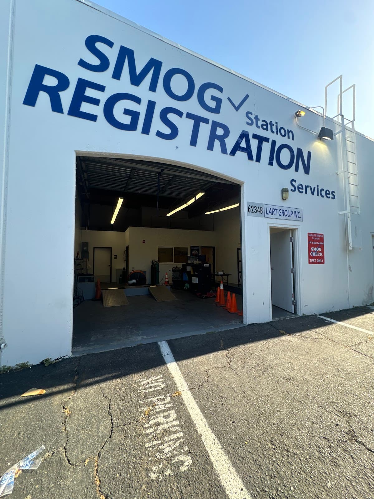 Open service bay under the SMOG Station Registration Services lettering, with inspection ramps and cones inside